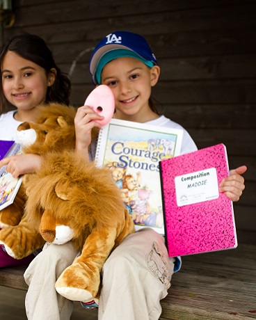 Kids smiling with stuffed animals and notebooks