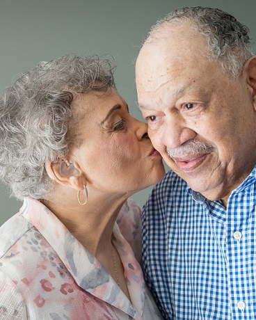 Elderly woman kissing man on cheek